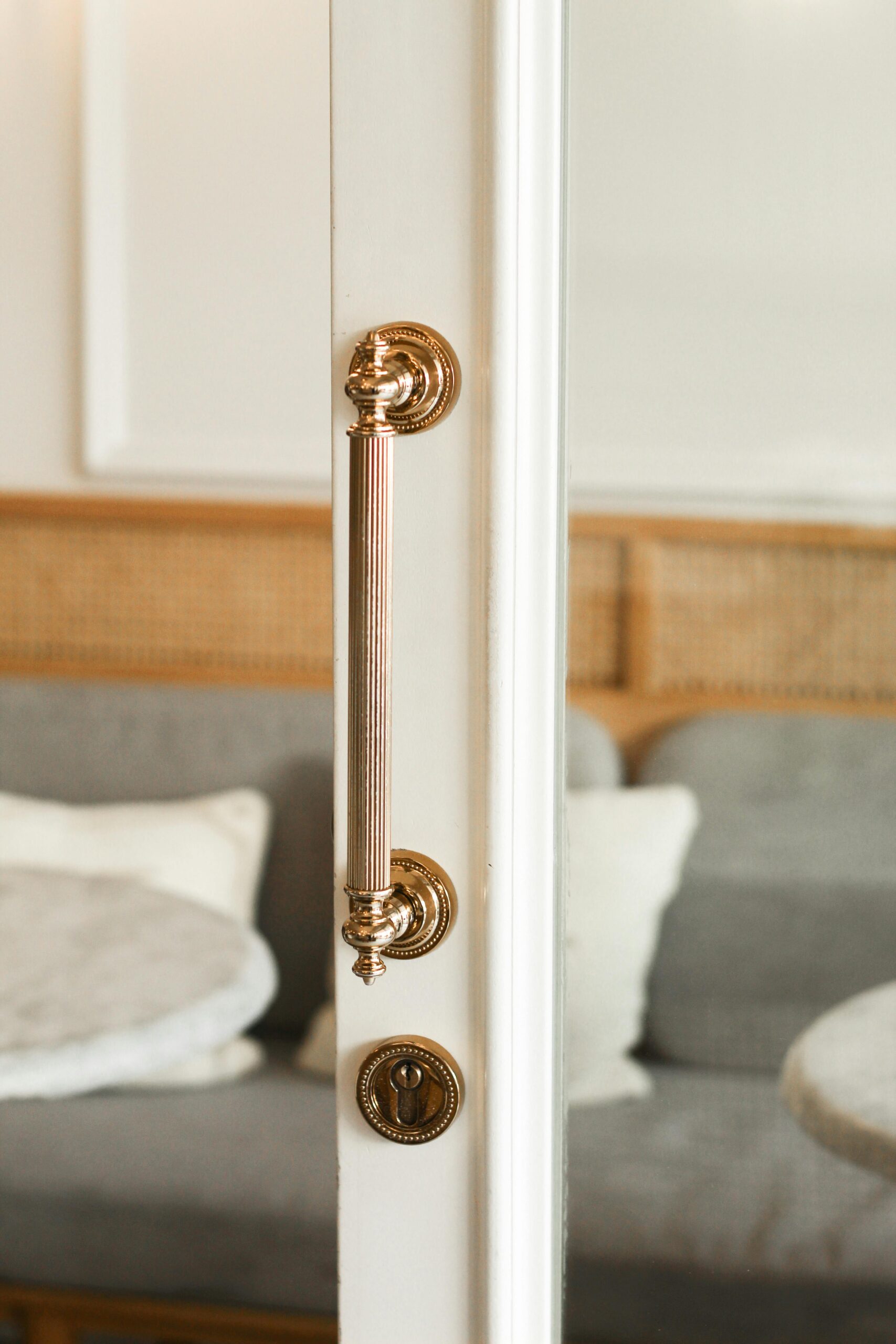 White glass door with decorative long gold pull handle and matching keyhole detail